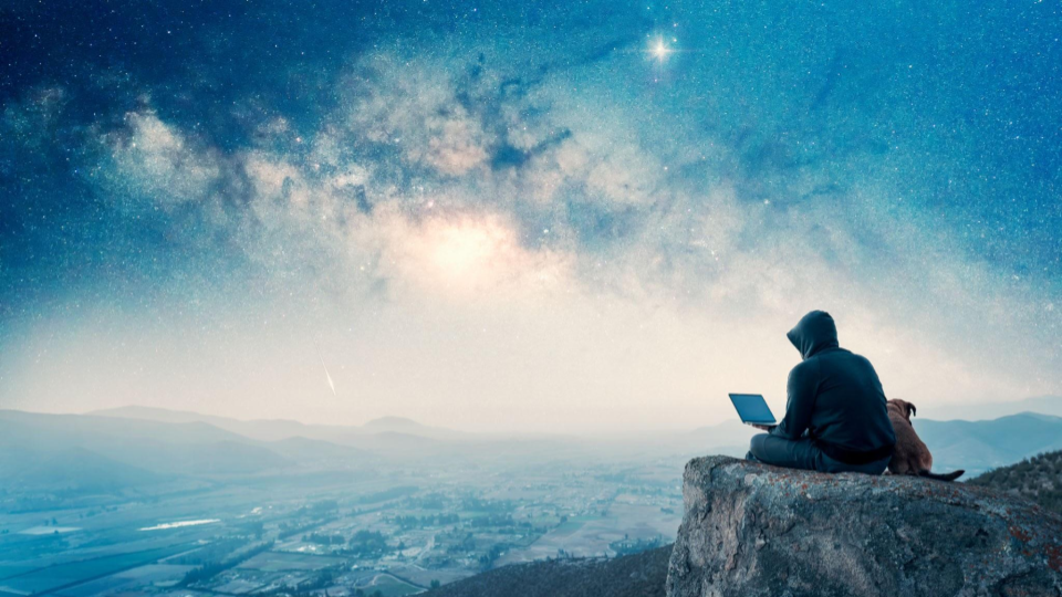 Osoba pracujaca z laptopem na tle nocnego nieba